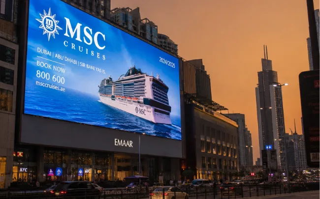 Outdoor LED screen supplier in Dubai showcasing a large illuminated LED video screen mounted on a commercial building facade at dusk.